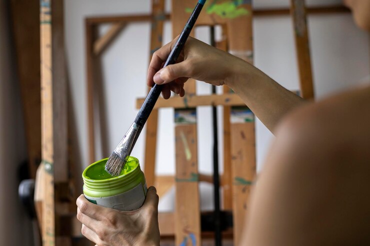Primer plano de las manos de una artista latinoamericana irreconocible colocando pintura en un pincel mientras pinta cuadros en un estudio de arte Concepto de artista y hobby