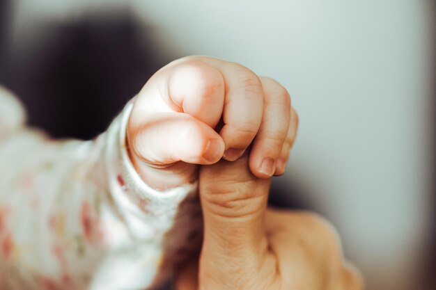 Foto primer plano de las manos del bebé sosteniendo el dedo de la madre