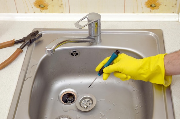 Foto un primer plano de las manos de un buen fontanero reparando el desagüe del fregadero de la cocina