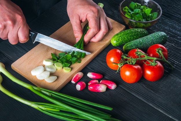 Primer plano de manos de chef corta cebollas verdes jóvenes C