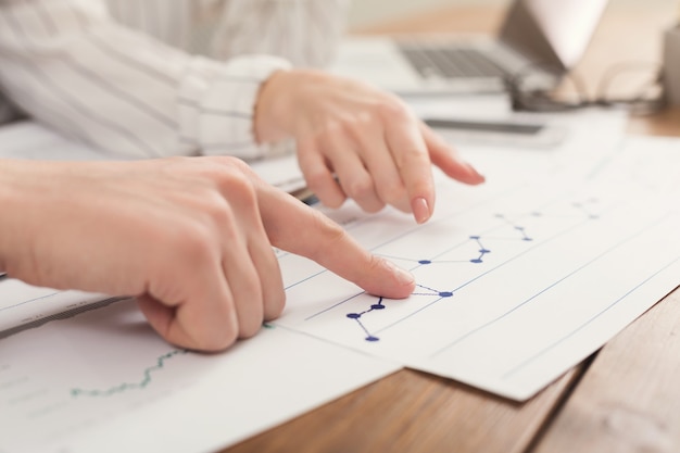 Foto primer plano de las manos de los colegas de negocios que controlan los diagramas y los resultados en los documentos. antecedentes financieros, contar y pagar una cuenta, espacio de copia