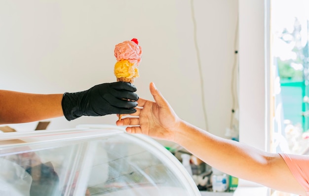 Primer plano de manos comprando un helado Primer plano de manos recibiendo un cono de helado Primer plano de una persona comprando un cono de helado