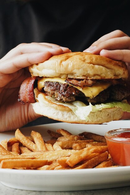 Foto primer plano de manos cortadas comiendo una hamburguesa