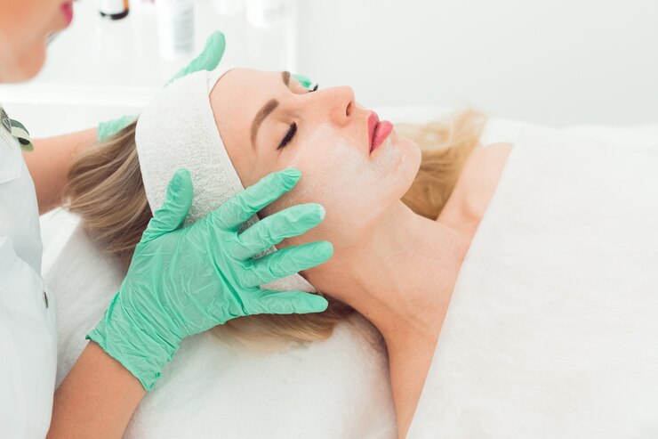 Primer plano de manos de cosmetóloga haciendo masaje facial a la hermosa joven cliente