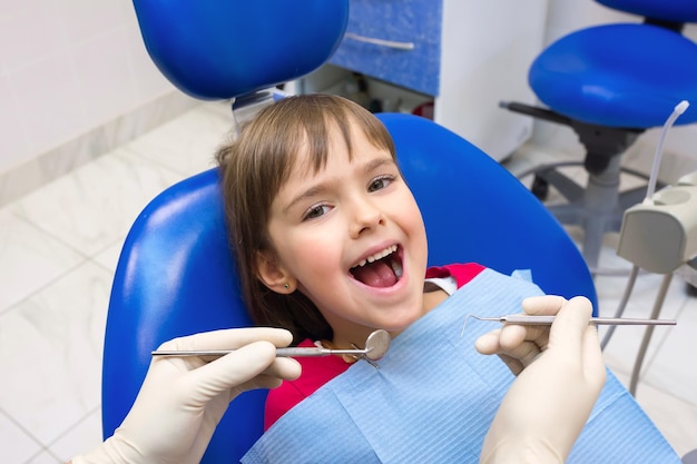 Un primer plano de las manos de un dentista y un niño con la boca abierta