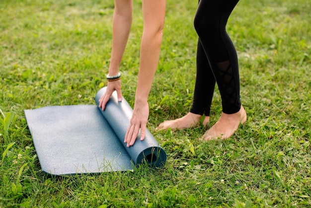 Foto el primer plano de las manos despliega la alfombra de yoga al aire libre. una mujer joven, una fuerte y exitosa entrenadora deportiva.