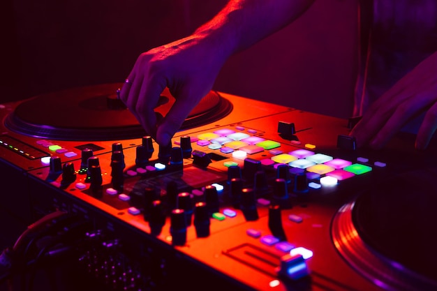 Primer plano de las manos de DJ en el mezclador de consola de dj durante el concierto en el club