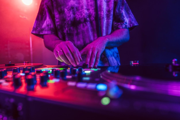 Un primer plano de las manos del DJ en el mezclador de la consola de DJ durante un concierto en el club