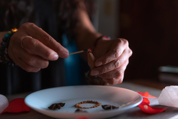 Foto primer plano de manos encendiendo una bruja de incienso en el día de los muertos realizando un ritual de limpieza creencias espirituales de halloween magia blanca