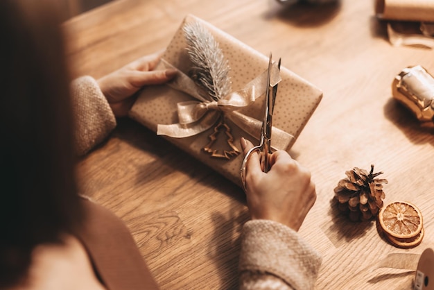 Primer plano de manos envolviendo regalos para Navidad decoración elegante colores cálidos vintage