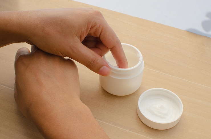 Foto primer plano de las manos extendiendo una crema humectante para promover una piel sana y nutrida.
