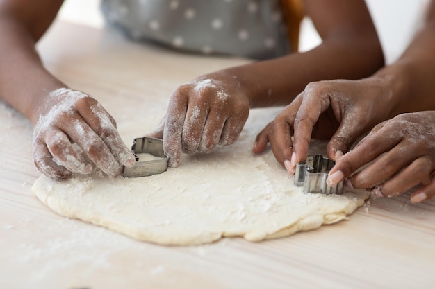 Primer plano de manos de la familia negra con cortadores de galletas