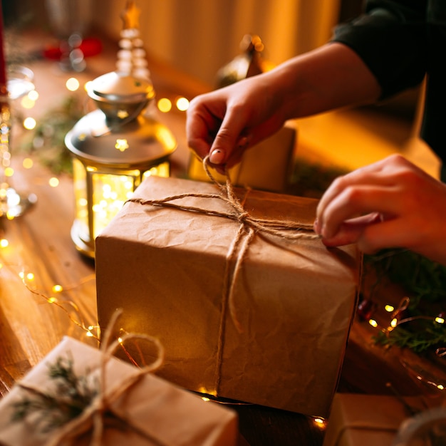 Primer plano de manos femeninas atar caja de regalo de artesanía navideña