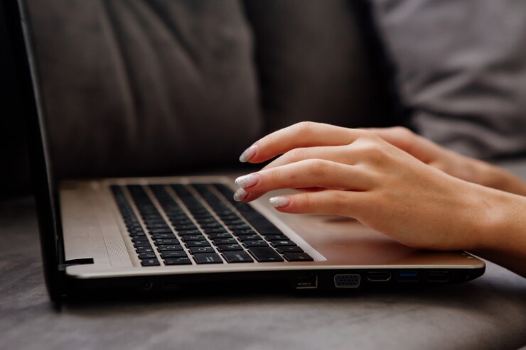 Foto primer plano de manos femeninas bien cuidadas con manicura en un teclado de computadora portátil