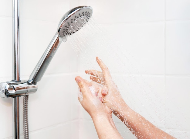 Primer plano de manos femeninas con espuma bajo la ducha