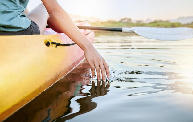 Primer plano de manos femeninas en kayak y sintiendo el agua del lago durante el día Mujer joven activa disfrutando de la actividad acuática mientras está de vacaciones en verano Canotaje en el tranquilo lago al atardecer durante una escapada de fin de semana