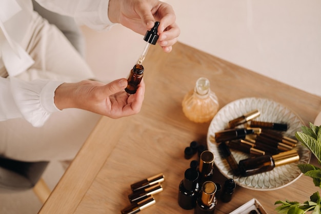 Primer plano de manos femeninas sosteniendo una botella de aromaterapia de aceite esencial