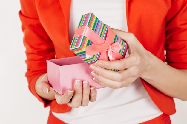 Primer plano de manos femeninas sosteniendo un regalo envuelto con cinta rosa