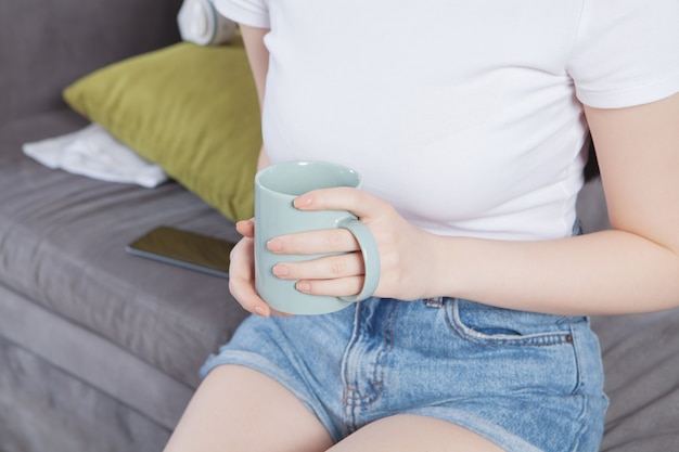 Primer plano de manos femeninas con una taza de bebida.