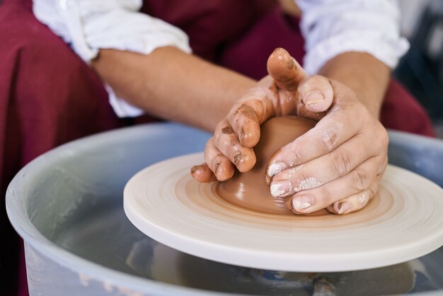 Foto primer plano manos femeninas tuercen la arcilla en un torno de alfarero