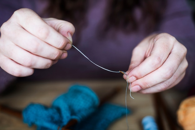 Primer plano de manos con hilo y aguja de coser herramientas