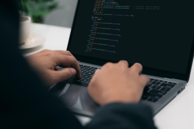 Primer plano de las manos de un hombre codificación HTML y programación en la pantalla de un portátil, desarrollo web, desarrollador.