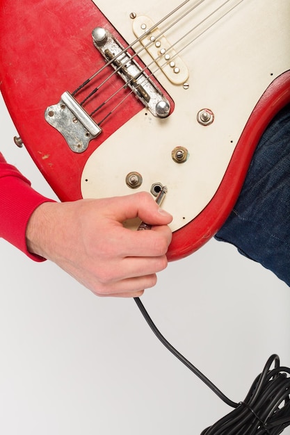 Primer plano de las manos del hombre con guitarra eléctrica roja