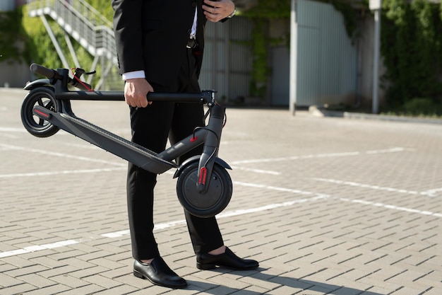 Primer plano de las manos de un hombre de negocios con un scooter eléctrico