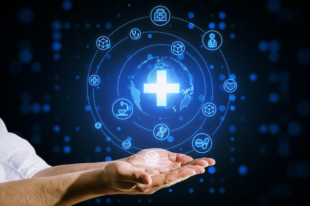 Primer plano de las manos de un hombre de negocios sosteniendo un holograma médico azul brillante creativo con una cruz y un globo sobre un fondo borroso Sistema de salud científica y concepto de farmacia futurista