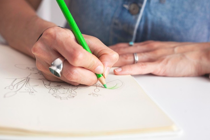 Foto primer plano de las manos de la ilustradora coloreando su trabajo.