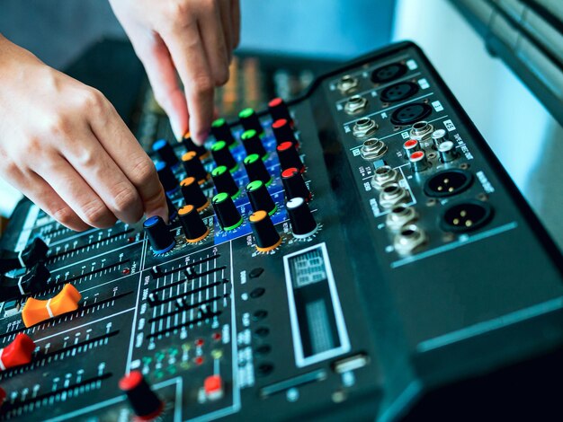 Foto primer plano de las manos del ingeniero de sonido ajustando el control de la mezcladora de sonido en un estudio de grabación de radiodifusiónsoud