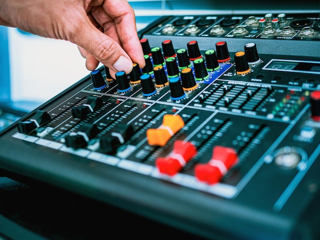 Foto primer plano de las manos del ingeniero de sonido ajustando el control de la mezcladora de sonido en la grabación de la prueba de sonido de radiodifusión