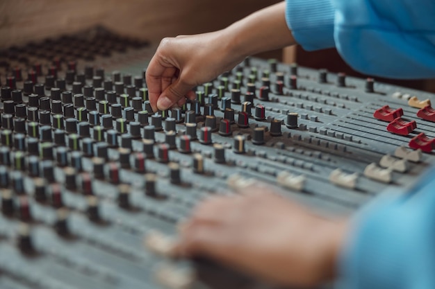 Primer plano de las manos del ingeniero de sonido usando el software de la mesa de mezclas para crear una nueva canción en la música profesional