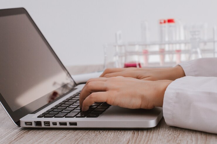 Foto primer plano de las manos del investigador médico escribiendo en el teclado del ordenador portátil