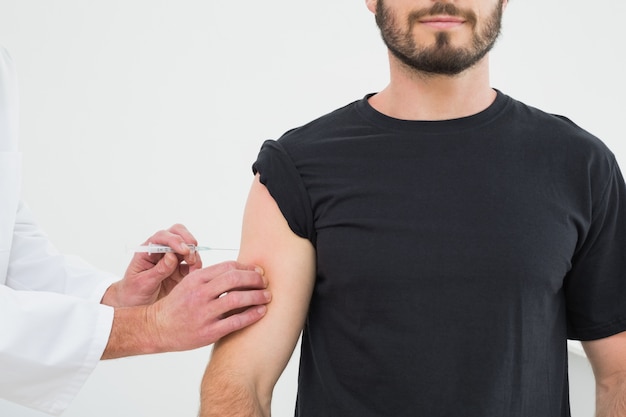 Primer plano de manos inyectando un brazo joven pacientes masculinos