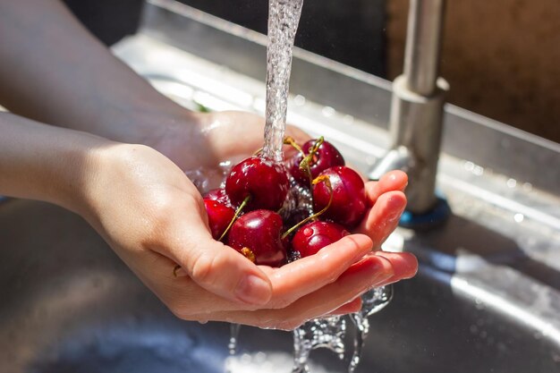 primer plano de las manos lavando la baya bajo el agua