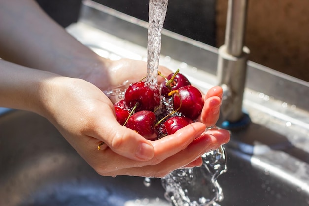 primer plano de las manos lavando la baya bajo el agua