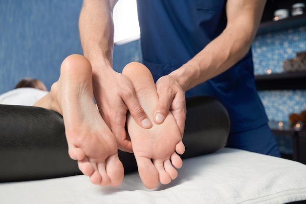 Primer plano de las manos del masajista masaje de pies de mujer en spa