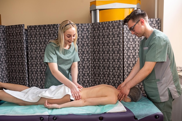 Primer plano de manos de masajistas masajeando la espalda de una persona en un salón de spa