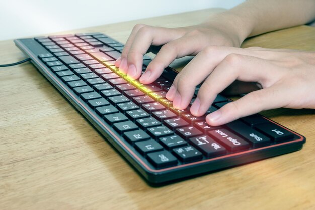 Un primer plano de manos masculinas escribiendo en un teclado negro. Un hombre de negocios trabajando en un concepto de efecto de luz.