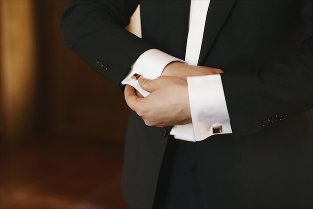 Primer plano de manos masculinas en un esmoquin preparación gemelos novio preparación antes de la ceremonia de la boda