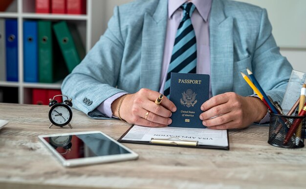 Primer plano de manos masculinas llenando documentos de visa en una mesa