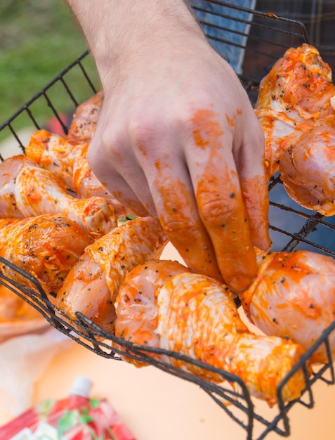 Primer plano de manos masculinas, se pone a la parrilla para freír pollo.