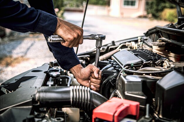 Primer plano de las manos del mecánico de automóviles usando la llave para el motor del coche de mantenimiento.