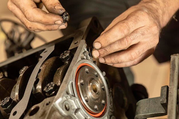 Primer plano de las manos de un mecánico montando meticulosamente un motor antiguo que muestra experiencia en la restauración