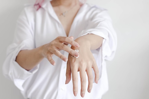 El primer plano de las manos de la mujer aplica hidratación para una piel sana, belleza, cuidado de la piel y cosmética.