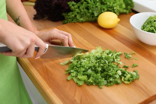 Primer plano de manos de mujer cocinando ensalada de verduras en la cocina. Comida saludable y concepto vegetariano.