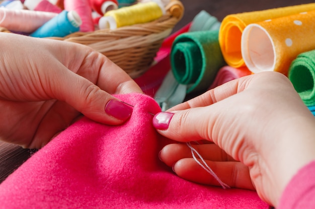 Primer plano de manos de mujer cosiendo juguete de color rosa hamdmade