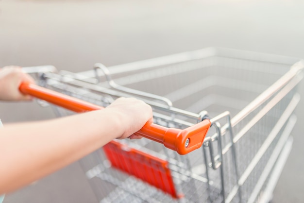 Primer plano de las manos de la mujer empujando un carro de la compra