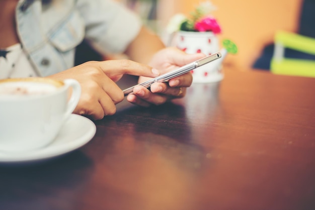 Primer plano de las manos de una mujer enviando mensajes de texto con su móvil en una cafetería